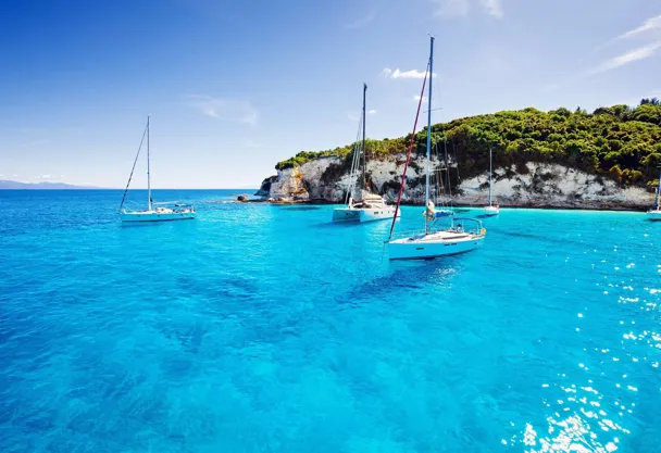 Turquoise and blue ocean with small green islands surrounded by white coasts and a speed boat sailing in the water